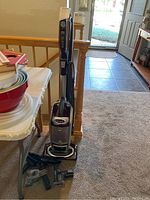 Full view of the Shark upright vacuum cleaner and several attachments placed on the floor beside it.