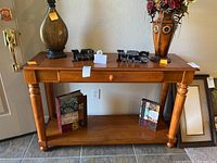 Full view of the wood sofa table with various decorative items on top and two books on the lower shelf.