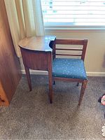 Full side view of the vintage wooden telephone table showing the seat and the shape of the tabletop.