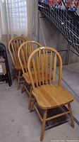 Set of three wooden chairs photographed in basement, side angle view showing all three chairs aligned.