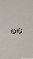 Two oval cut champagne green sapphires shown on a plain background, highlighting their color and clarity.