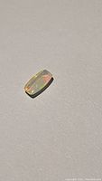 Close-up image of the 1.43ct Ethiopian opal gemstone showing its rectangular cabochon shape and vibrant internal color splashes.