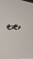 Pair of oval cut clear crystal quartz stones shown side by side on flat surface