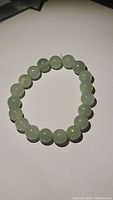 Full view of the green aventurine bead stretchy bracelet laid flat showing round beads and elastic string.