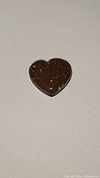 Close-up front view of heart-shaped red spotted jasper gem showing smooth polished surface and natural red spots on dark reddish background.