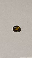Oval cut sapphire showing yellow and blue reflective tones under light, highlighting multicoloured nature.