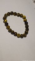 Polished round natural tigerseye beads bracelet arranged on a flat surface, showing color and pattern variations of the stones.