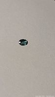 Clear image of the oval cut paraiba blue coloured tourmaline gemstone on a plain background, showing the deep blue hue and cut shape.