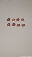 Eight oval pink opal cabochons arranged in two rows on white background showing natural color and inclusions