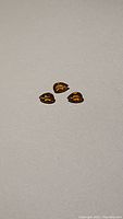 Three small pear-shaped bright orange spessartite garnet gemstones on a neutral background