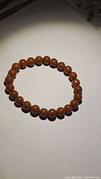 Photo of red jasper gemstone bracelet lying flat showing the round polished reddish-brown beads.