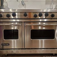 Front view of stainless steel gas range with eight control knobs and two oven doors