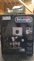 Front of original box showing DeLonghi branding and image of machine with two espresso cups