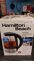Box front showing Hamilton Beach branding, product name, and kettle image with visible removable tea infuser inside.