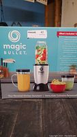 Front of Magic Bullet box showing blender and prepared smoothies with ingredients.