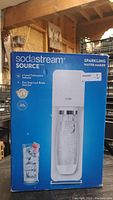 Front view of SodaStream Source box showing the product image and key features such as 3-level carbonation and easy snap-lock bottle insertion.