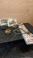 Wide shot showing four vintage pulleys placed on a black table with wooden motivational signs in background.