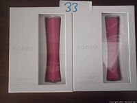 Two boxed Foreo Espada acne treatment devices, pink color, side-by-side on a dark surface.