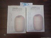 Two boxes of bottle humidifiers shown, each with image of a round bottle-shaped humidifier unit on the front and text in English and another language.