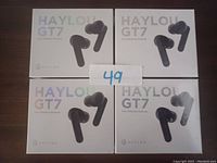 Four boxed sets of Haylou GT7 True Wireless Earbuds placed on a flat surface with a paper displaying number 49 in front.