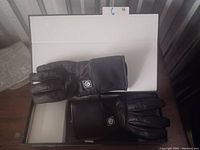 Photo showing a pair of medium-sized black heated gloves in an open box on a table.