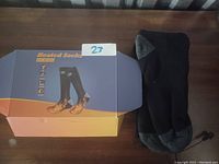 Photo of the heated socks alongside the original box on a wooden surface.