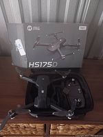 Holy Stone HS175D drone with four propellers, remote control, carrying case, and original box displayed on wooden surface.