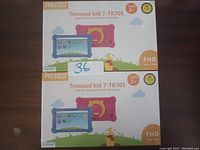 Two boxed REZQ Tronpad Kid 7-TK701 tablets are shown, one with a pink protective case and one with a blue protective case, each tablet sized 7 inches with full HD display.