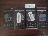 Photo showing four boxed Bumpco wireless headsets model PB-01 in black and blue, sealed in retail packaging with barcode labels attached.