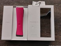 Photo of the pink Foreo Espada blue light acne treatment device in its original white box packaging on a wooden surface.