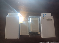 Photo shows a rechargeable silver hand warmer in its plastic packaging, a white box on each side, and a USB charging cable in front.