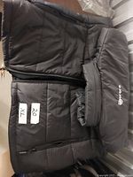 Black heated vest laid flat showing front zipper and size tags XL and 20 with Ororo logo on collar area.