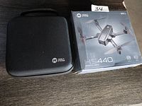 Photo of the drone box and the black hard carrying case with Holy Stone logos on a dark wooden surface.