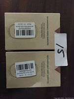 Two cardboard boxes of rechargeable hand warmers, each with a barcode sticker and 'Made in China' label. Boxes are beige with product labeling.