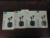 Four boxed Usams TWS IA Series Bluetooth earbuds sets displayed in a row on a dark surface. Boxes show earbuds and charging cases through front windows.