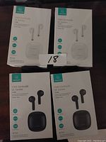 Photo showing four boxed USAMS IA Series TWS earbuds, two in white packaging and two in black, all sealed.