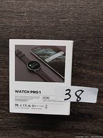 Box back showing Watch Pro1 smartwatch with black band next to smartphone, with technical and certification info.