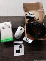 Photo showing the white wired mouse with scroll wheel, original JITOPKEY box, WiFi endoscope device components including camera cable, batteries, and manual on a wooden surface