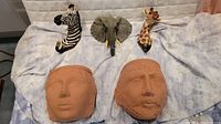 All five items displayed together on fabric background showing zebra, elephant, giraffe animal hooks and two terra cotta planter heads.