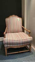 Front view of the French Provencal style armchair showing striped upholstery and wood frame with decorative arms and scalloped backrest.