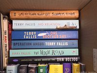 Books including titles by Terry Fallis and David Sedaris stacked in a box