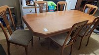 Six wood dining chairs around a wood table in a basement setting
