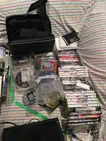 Full lot overview showing carrying case, Gameboy Color handheld system, assorted video game cases, original manuals, and accessories arranged on bedspread.
