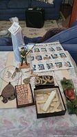 Overview of Judaica collection laid out on table including soldier figurine, Hebrew letter cloth, candle, brass piece, mezuzah, and other items