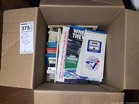 Box filled with various Toronto Blue Jays media guides, showing tops of multiple booklets and spiral-bound guides, logo and branding visible.