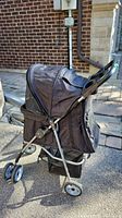 Side view of black VIV pet stroller showing fabric canopy, wheels, and storage basket under the seat.