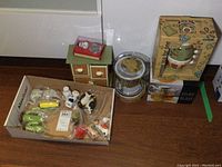 Wide view showing box with multiple whimsical salt and pepper shakers and boxed teapot sets on floor