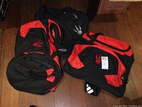 Two Toronto Raptors sports bags, primarily black with red accents, showing Raptors claw logo and Adidas branding on one bag.