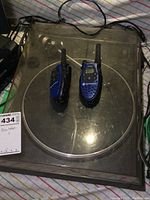 Top-down photo showing ULM Dual turntable with transparent dust cover and pair of blue Motorola Talkabout T5720 walkie talkies on top.
