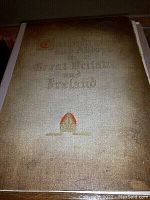 Photo of a large 1890s book cover titled 'Cathedrals and Abbeys of Great Britain and Ireland' with faded, gold-colored lettering and an orange bishop's mitre emblem.